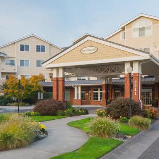 A welcoming entrance to a multi-story building with well-maintained landscaping and a pathway.