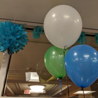 A festive display of colorful balloons and paper pom-poms, perfect for a celebration.