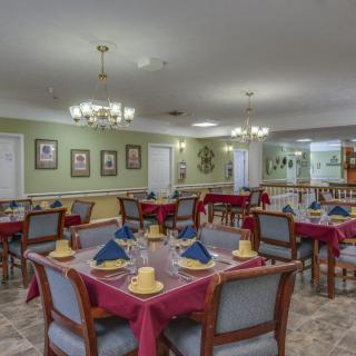 A well-decorated dining area with multiple tables set for a meal, featuring chandeliers and elegant decor.