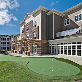A modern residential building with a golf putting green in the foreground.
