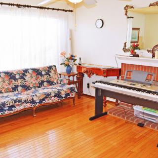 A cozy living room with a piano and floral-patterned couch.