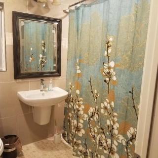 A cozy bathroom with a floral-patterned shower curtain and a white sink beneath a framed mirror.