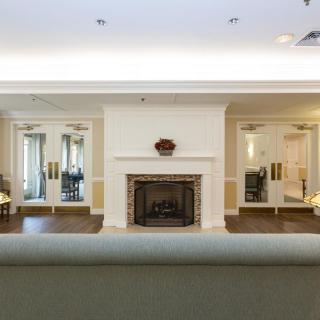 A cozy living room featuring a central fireplace, mirrors on either side, a chandelier, and comfortable seating.