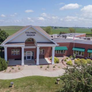 Aerial view of a red brick building with columns, identified as a library, surrounded by landscaping.