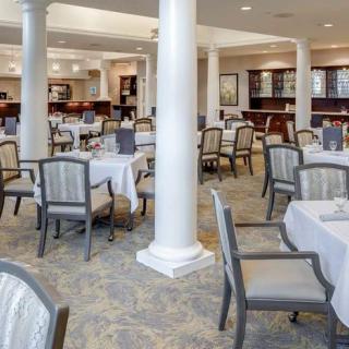 A spacious dining room with elegantly set tables and chairs, featuring classic interior design elements.