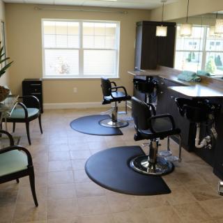 A modern hair salon interior with styled chairs and workstations.