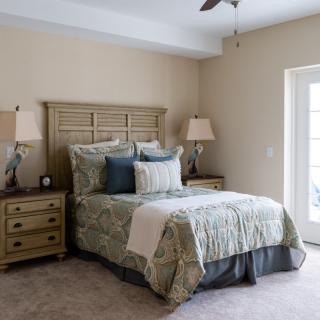 A cozy, well-decorated bedroom featuring a bed with patterned bedding and matching nightstands with lamps.