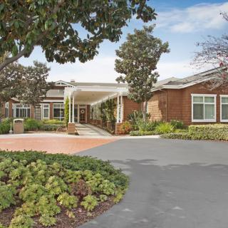 A welcoming entrance to a brick building with well-maintained landscaping and a driveway.