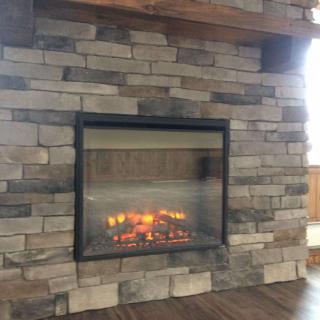 A stone fireplace with a cozy fire burning inside, adding warmth to the home's interior.