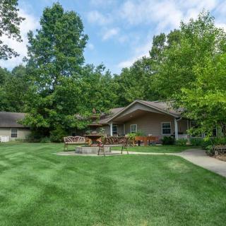 A cozy house with a well-maintained lawn and patio, surrounded by lush trees.