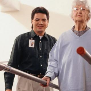 An elderly person undergoing physical therapy with the assistance of a healthcare professional.