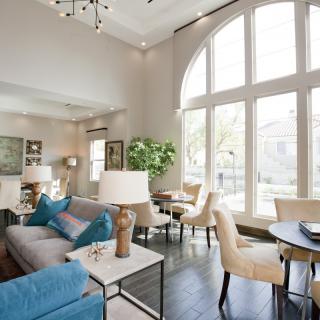A modern living room with elegant furniture and large arched windows, featuring a mix of neutral and blue accents.