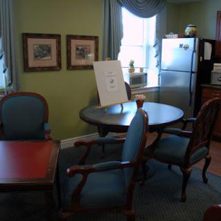An inviting office space featuring a table with chairs, a refrigerator, and framed artwork on the walls.