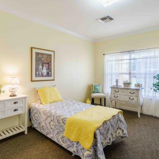 A cozy bedroom with a single bed featuring yellow accents and elegant decor.