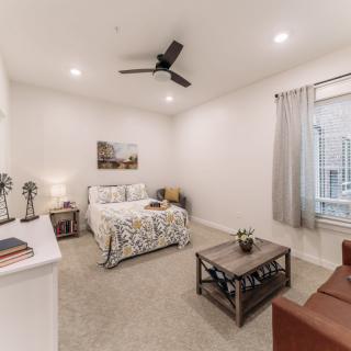 A modern and minimalist bedroom with a cozy bed, nightstand, and ceiling fan.