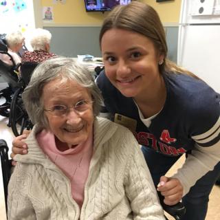 A joyful moment shared between a caregiver and an elderly resident in a nursing home.
