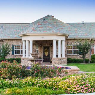 A beautiful house with a landscaped garden and columned entrance.
