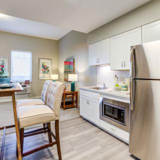 A modern kitchen in an apartment featuring stainless steel appliances and a small dining area.
