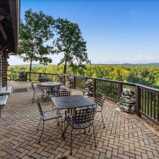 A scenic outdoor patio with tables and chairs overlooking a lush forested area.
