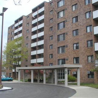A multi-story apartment building with a brick facade and a covered entrance.