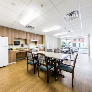 A modern kitchen and dining area with wooden cabinets, a refrigerator, and a table with chairs.