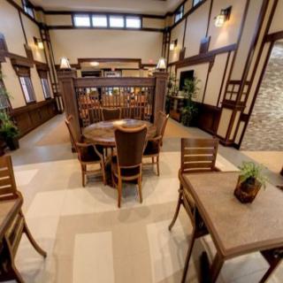 An elegantly designed restaurant interior featuring wooden tables and chairs, with decorative plants and ambient lighting.