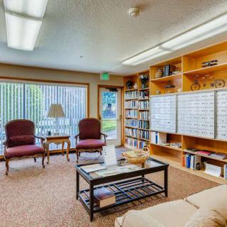 Cozy library room with bookshelves, chairs, and a glass table.