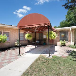 A welcoming entrance to a home featuring a decorative canopy and well-maintained landscaping.