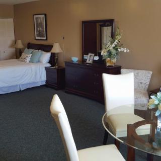 A well-furnished hotel room with a bed, table, and chairs.