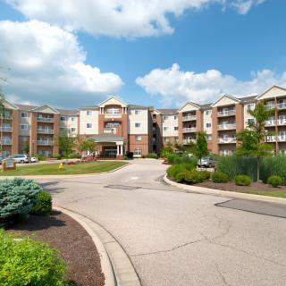 A modern apartment complex surrounded by landscaped gardens under a partly cloudy sky.