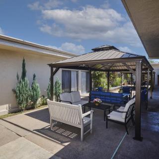 A cozy outdoor seating area with a gazebo in a sunny backyard.
