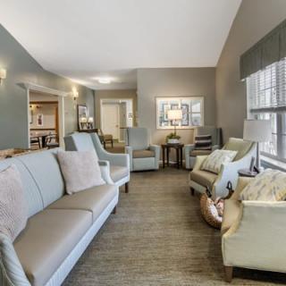 A cozy living room with elegant sofas, chairs, and large windows letting in natural light.