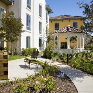 A well-maintained garden area with a gazebo and benches outside a residential building.