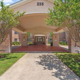 Covered entrance to a building with surrounding greenery.
