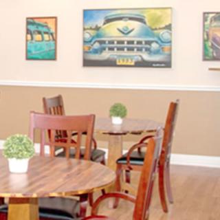 A cozy indoor cafe seating area with wooden tables, chairs, and artistic wall decor.