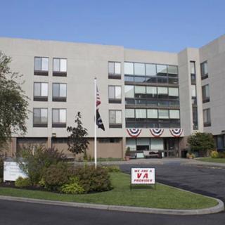Exterior view of a VA hospital with flags and landscaping.