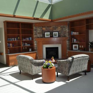A cozy living room with a fireplace, armchairs, and built-in bookshelves.