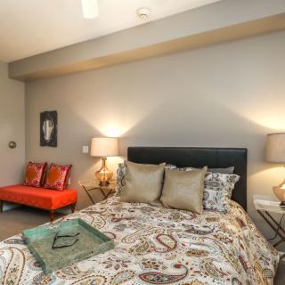 A modern and cozy bedroom with stylish decor, featuring a bed with patterned bedding and two lamps on bedside tables.