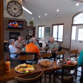 A group of seniors enjoying a casual gathering in a community room with food and drinks.