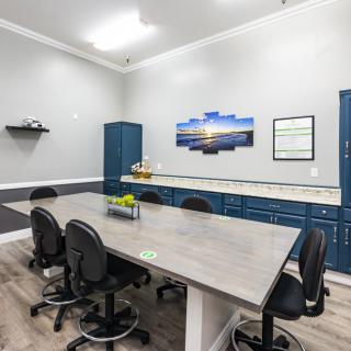 A modern conference room with a long table, several chairs, and cabinets along the wall.