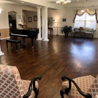 A spacious living room with a grand piano, elegant furniture, and wooden flooring.