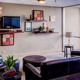 A modern living room with stylish furniture, wall-mounted shelves, and a flat-screen TV.
