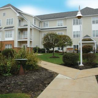 A modern residential apartment complex with landscaped gardens and a walkway.