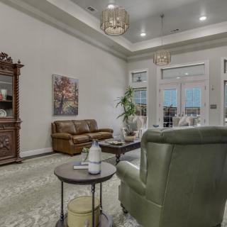 A cozy living room with elegant furniture and tasteful decor, featuring a sofa, armchair, coffee table, and wall art.
