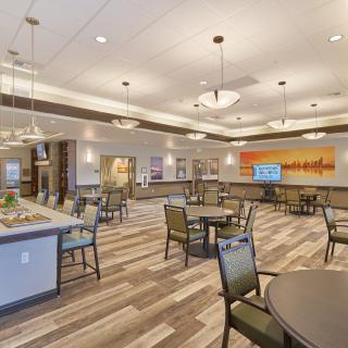 A modern dining area with neatly arranged tables and chairs, featuring elegant lighting fixtures.