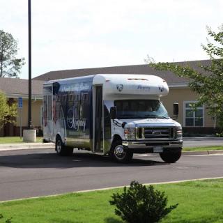 A small bus parked in front of a building on a sunny day.