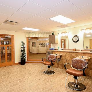 A well-lit salon interior with comfortable chairs and mirrors.