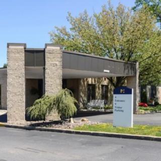 Front view of a healthcare facility entrance with visible signage and surrounding trees.