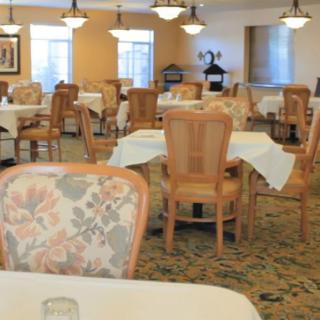 A well-lit dining room with neatly arranged tables and chairs.