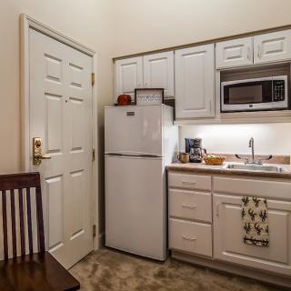 A small kitchen area with a refrigerator, microwave, and sink.